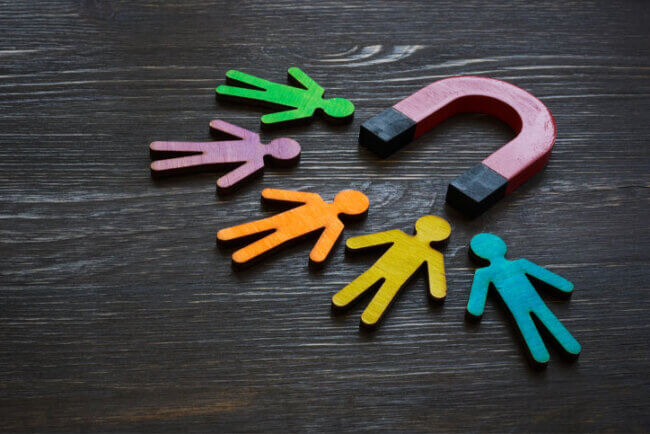 A magnet attracting wooden cutouts of people.